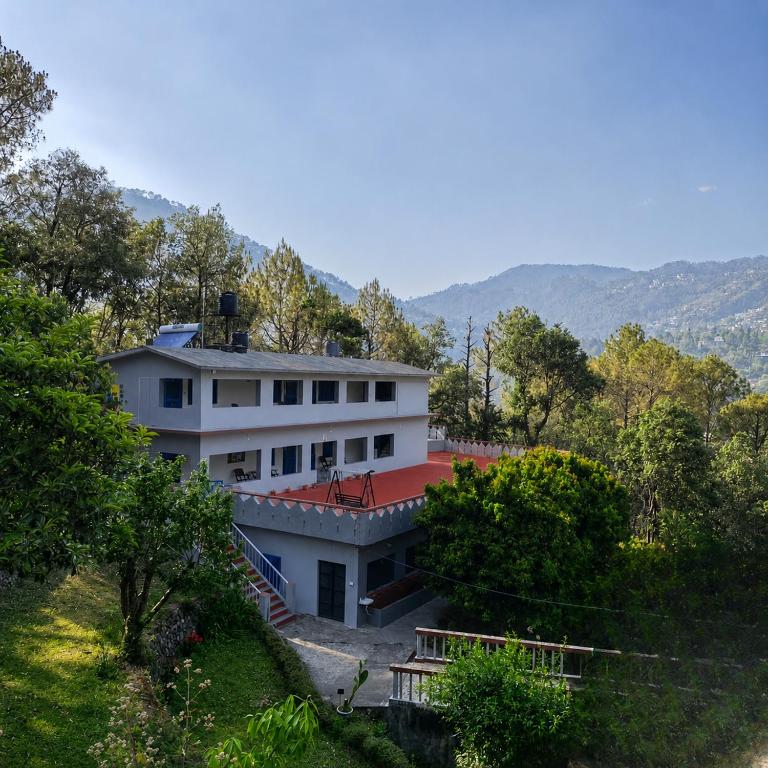a white house with a red roof and trees at Aranya Tara in Bhīm Tāl