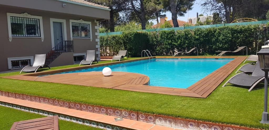 a swimming pool in a yard with chairs and a house at Espaciosa villa con piscina, ideal para relajarse en familia in Los Hueros