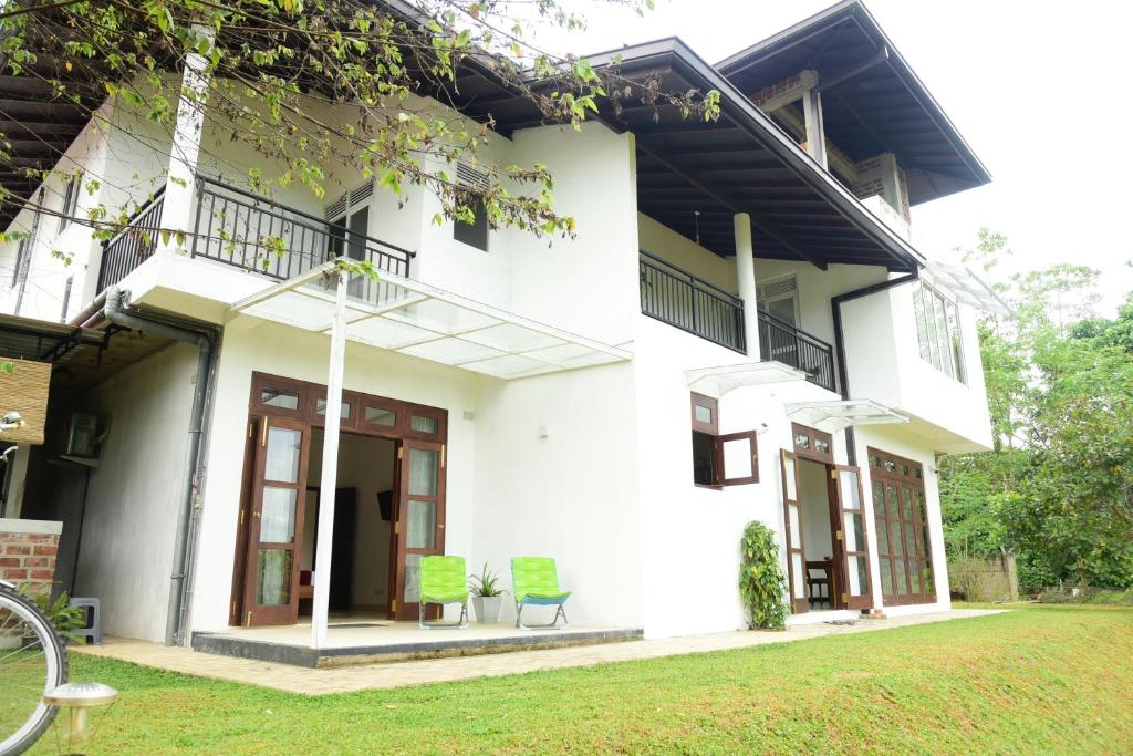 a white house with two chairs in a yard at Ayurishi Villa in Hikkaduwa