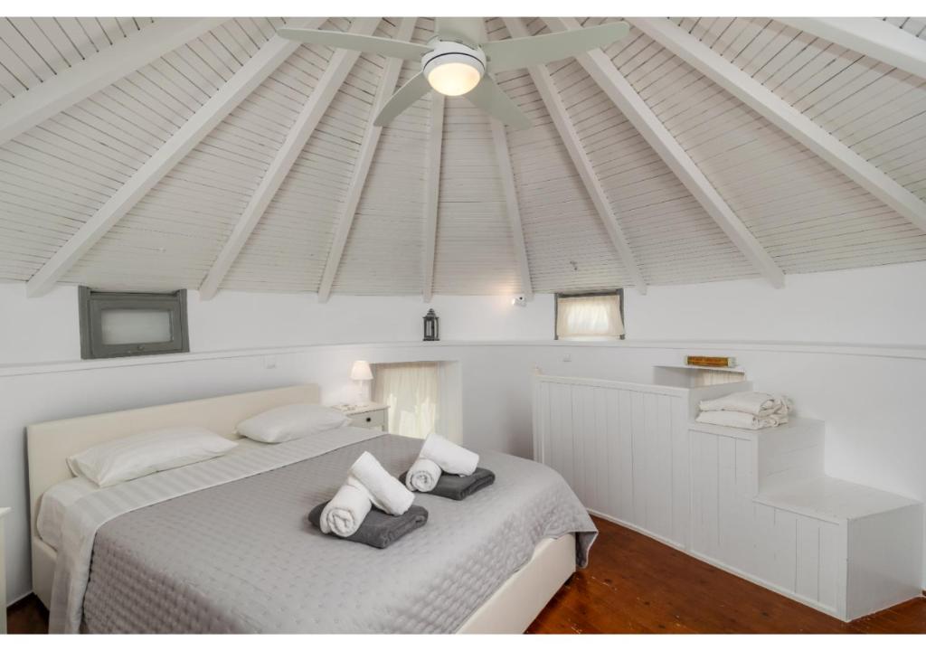 a bedroom with a white bed with a ceiling at WindMilos in Tripiti
