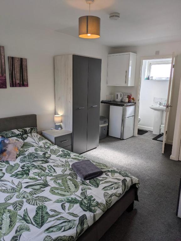 a bedroom with a bed with a green and white blanket at Corby Double & En-suite Rooms NN17 2LZ area Ideal Contractors Short & Long stays Opposite Lodge Park Leisure Center in Corby