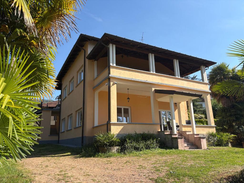a yellow house with palm trees in front of it at Vista Bella - Villa Giulia in Porto Valtravaglia
