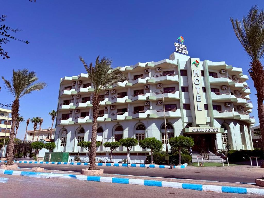 a large hotel with palm trees in front of it at Green House Hotel in As Suways