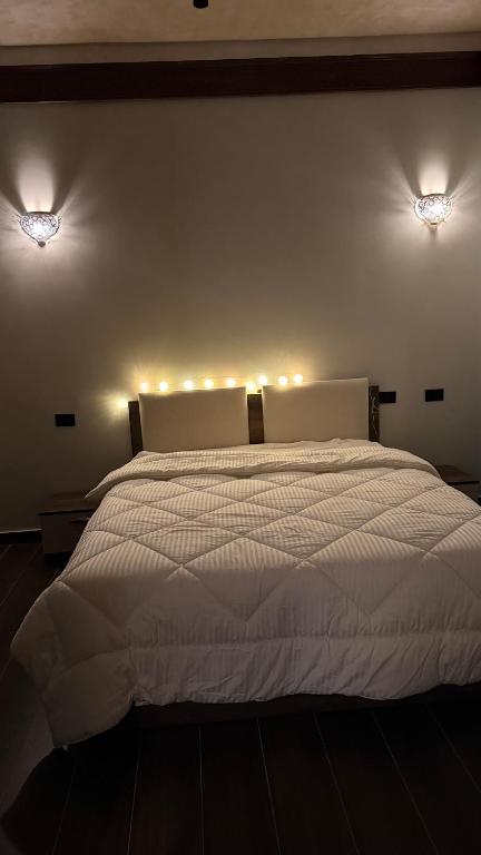 a bedroom with a white bed with lights on the wall at Jessica's House in Luxor