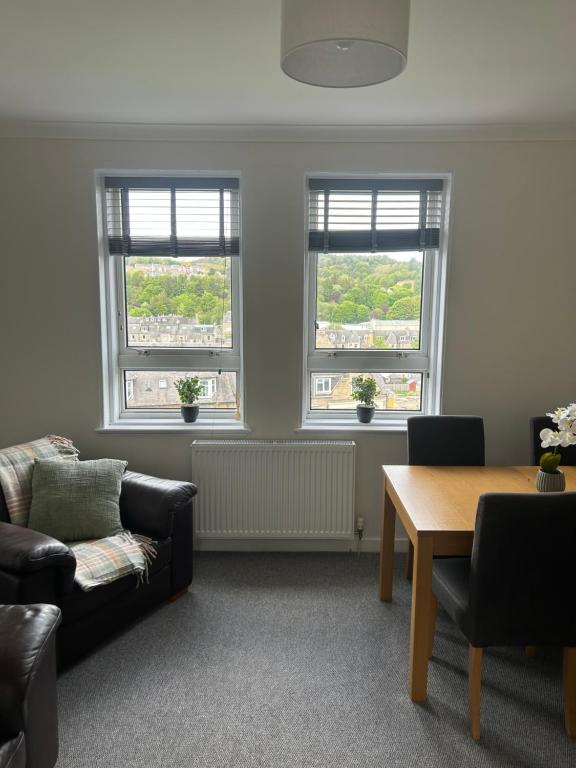 a living room with two windows and a table at Kilnhill in Hawick