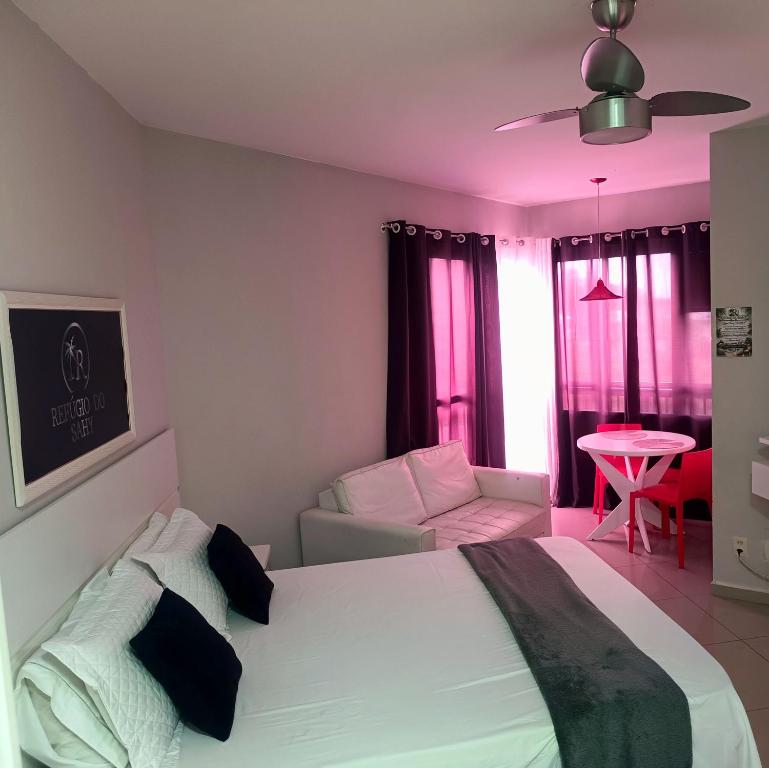 a bedroom with a white bed and a couch at Loft no Refúgio do Sahy in Mangaratiba