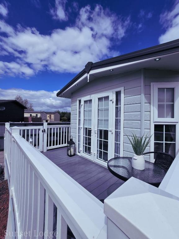 a large deck with a table on a balcony at Sunset lodge 32 in West Thirston