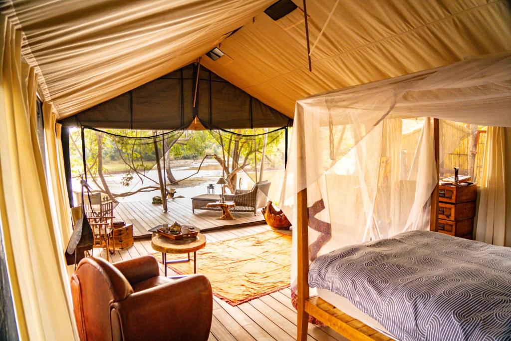 a bedroom with a canopy bed and a chair at Painted Dogs Lagoon in Kakumbi