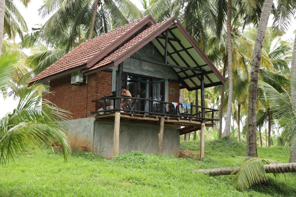 a house with a balcony with a person on it at Aji fruit farm cottage peaceful lakeside farm stay with sunrise views 03 in Embilipitiya