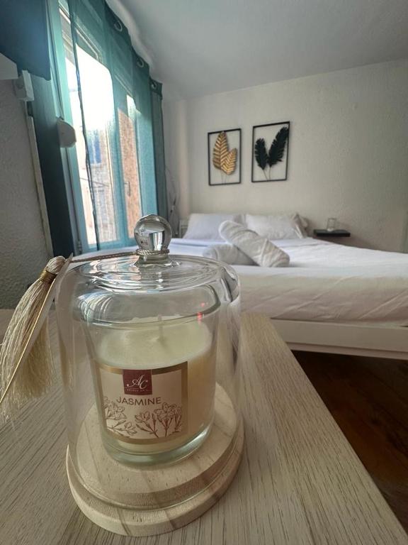 a candle in a glass container on a table in a bedroom at La plume d'or in Saint-Étienne