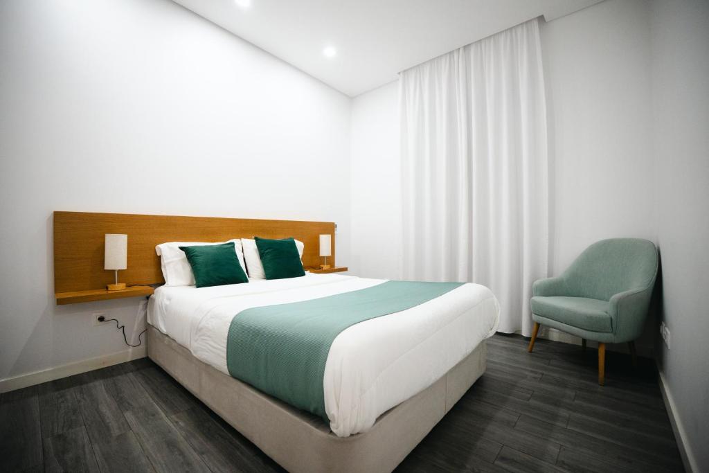 a bedroom with a large bed and a blue chair at Casa das Ondas in Ribeira Grande