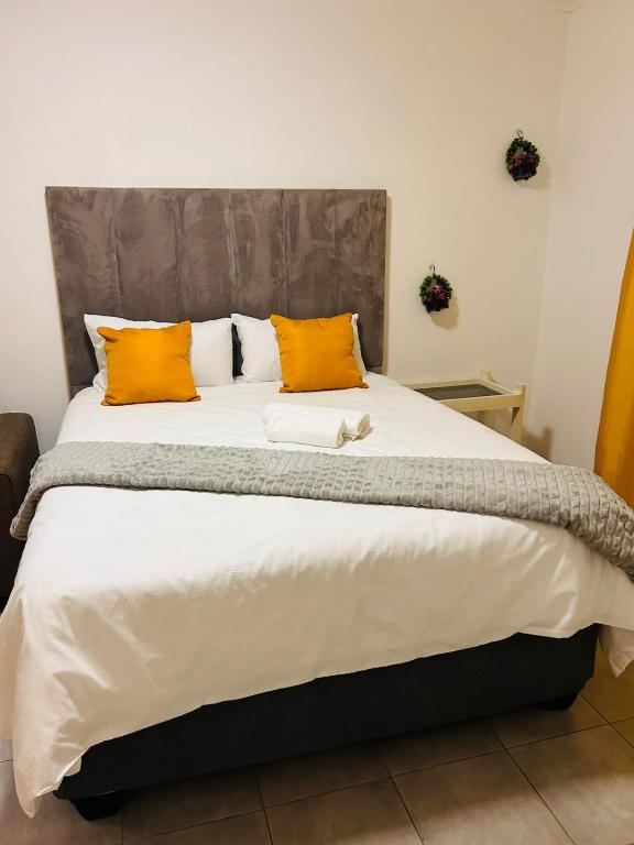 a bedroom with a large bed with orange pillows at MandA Cozy GuestHouse in Middelburg