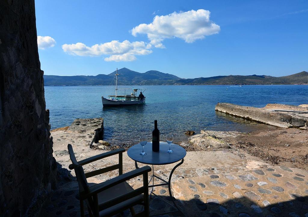 a table with a bottle of wine and a boat in the water at Salty Splash in Klima