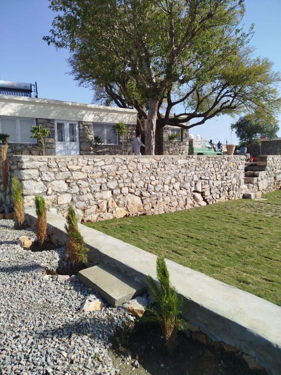 a stone wall and a house with a tree at HYN Mountain Resort in Kohāla
