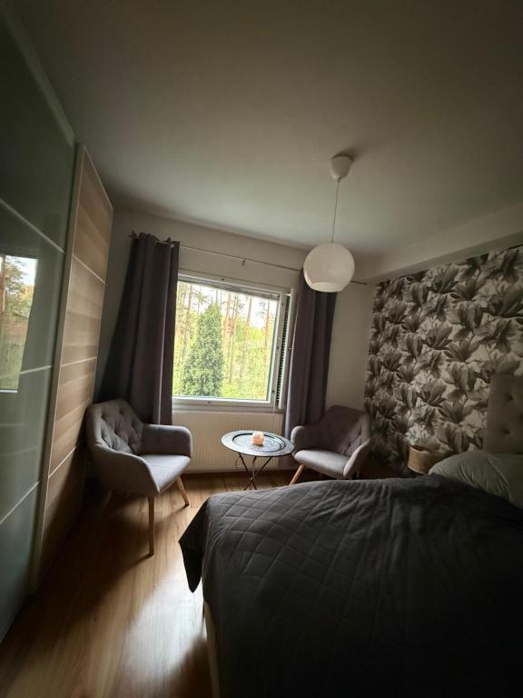a bedroom with a bed and two chairs and a window at LIS Apartment in Naantali