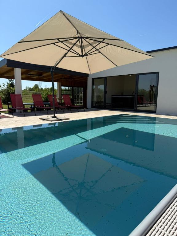 a swimming pool with an umbrella and chairs at House on the river in Karlovac