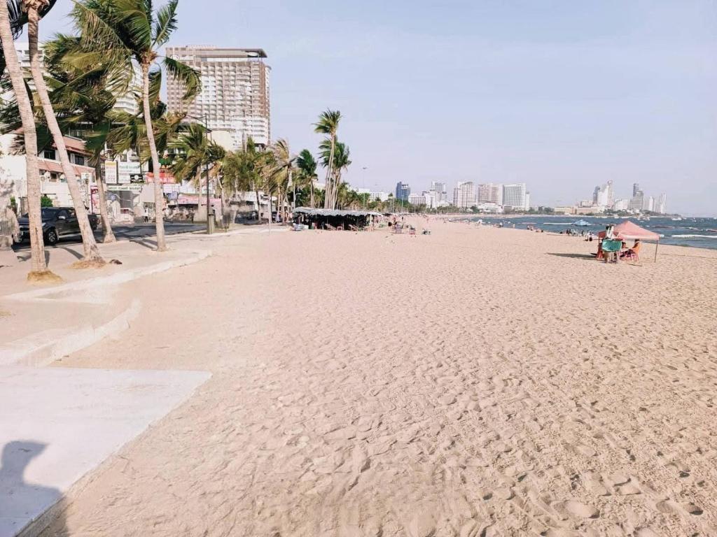 a sandy beach with palm trees and the ocean at Beautiful Sandy Jomtien Beach Pattaya at NeO Seaview Condo in Jomtien Beach
