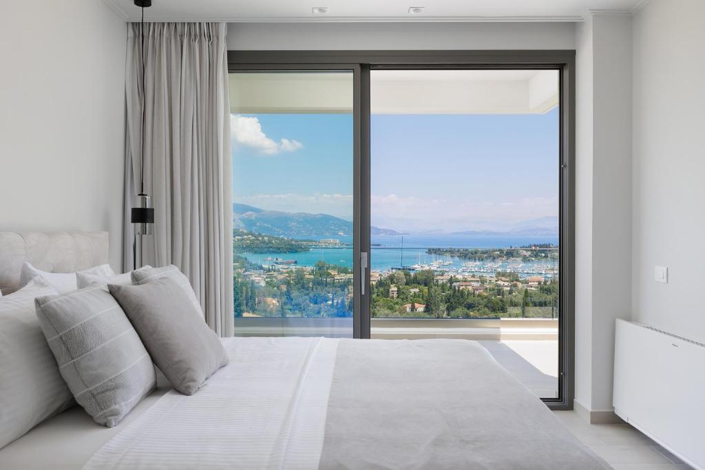 a bedroom with a large white bed with a large window at Villa Eleni Di Mare in Kontokali