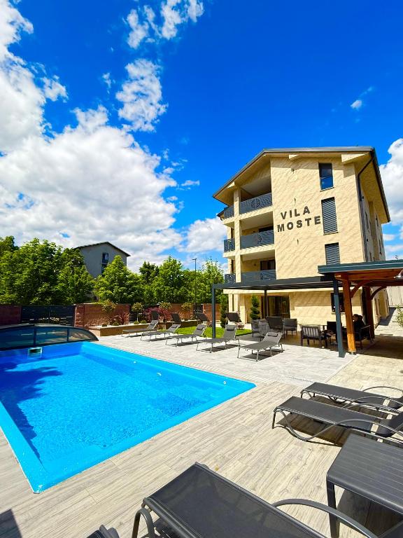 a swimming pool with patio furniture and a building at Villa Moste Ljubljana - Modern apartments with Pool, EV station & free parking in Ljubljana