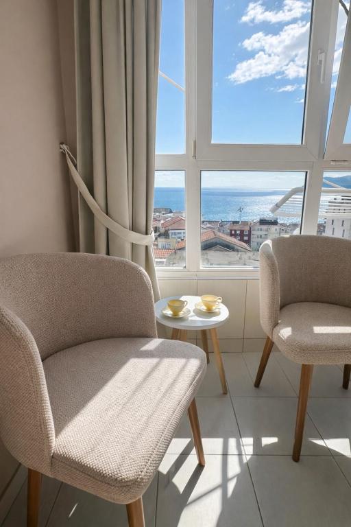 a living room with two chairs and a table and a window at Sea View Apartment Rafailovići in Rafailovici
