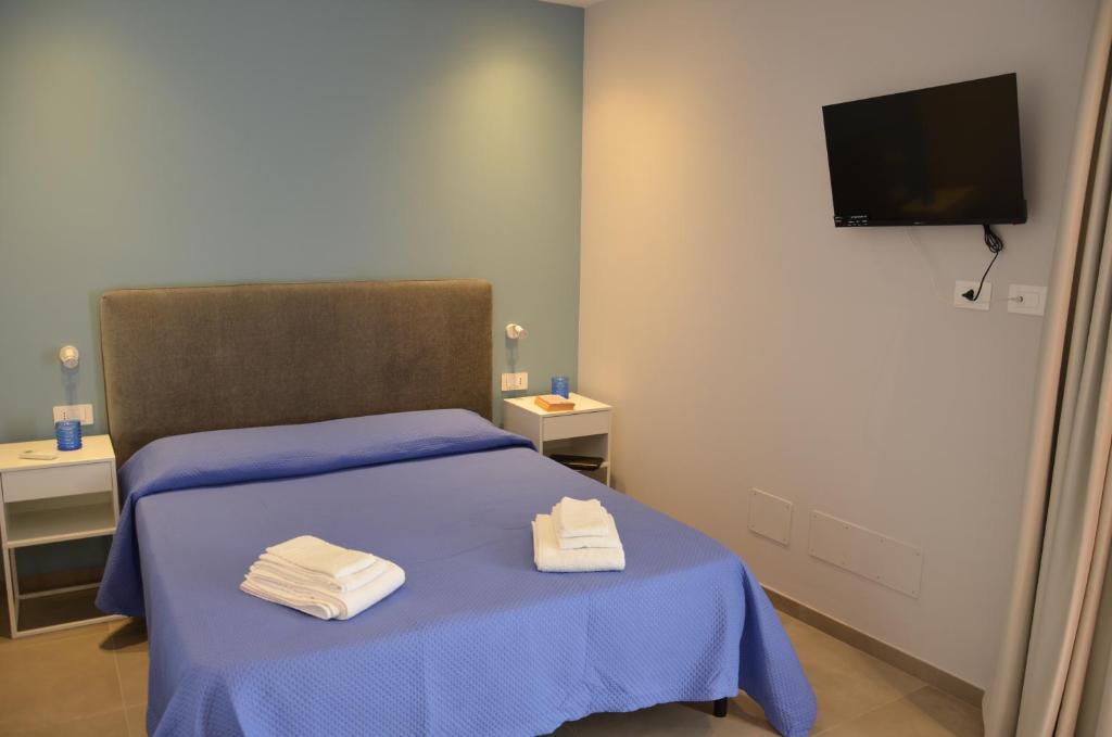 a bedroom with a blue bed with towels on it at La Porta Rossa House in Castelbuono