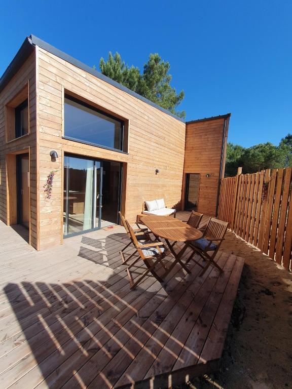 a wooden deck with a wooden table and chairs at Surf & Sauna Bud House in Longeville-sur-Mer