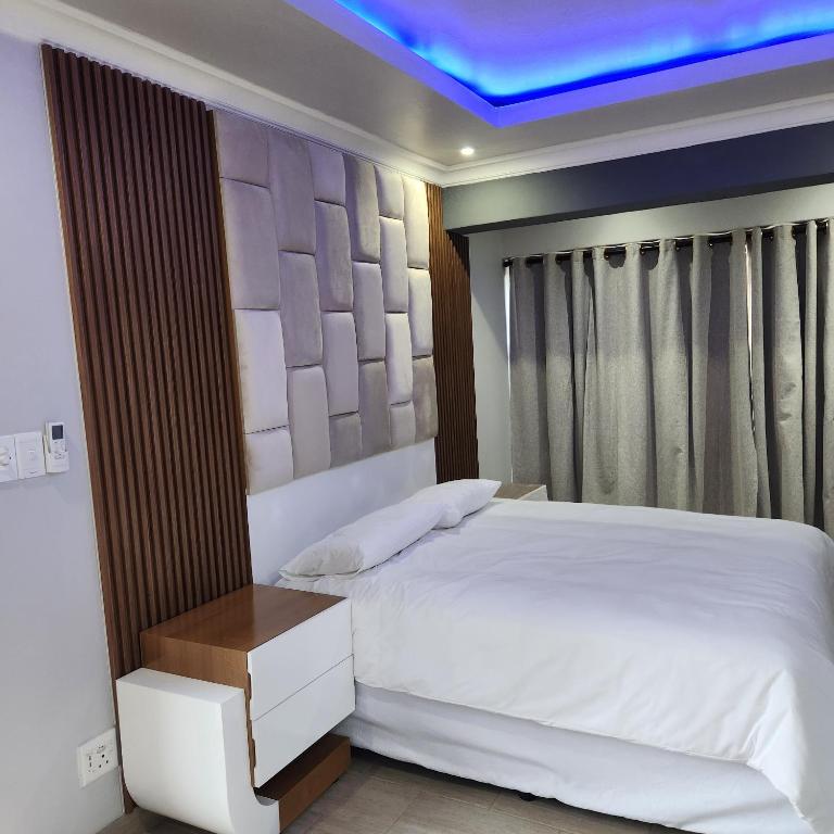 a bedroom with a white bed and a blue ceiling at Cozy & Modern Apartment -Self Catering in Pretoria