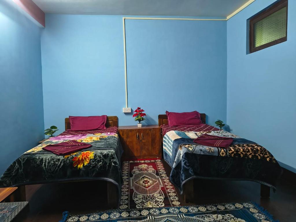 two beds in a room with blue walls at Laxmi Homestay in Kalimpong