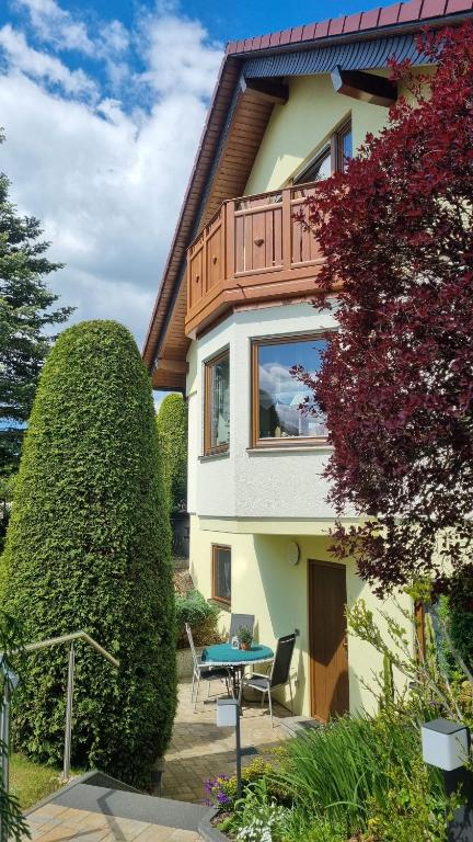 a house with a balcony and a table in front of it at Ferienwohnung Sonnenblick in Bischofswerda