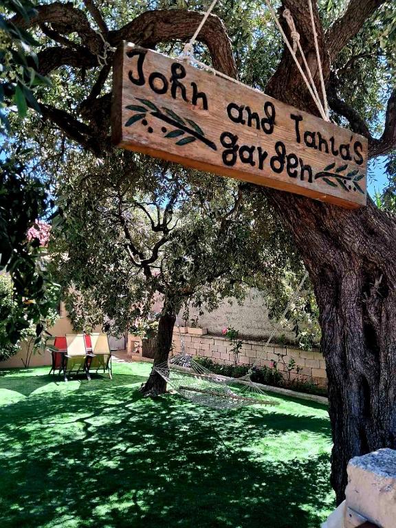 a sign hanging from a tree in a park at John and Tania's Garden in Prinos