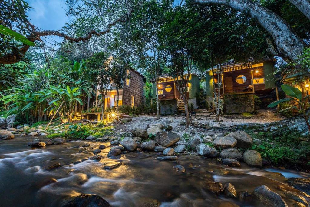 a house with a river in front of it at The ForRest Peace Forest แม่กำปอง in Ban Huai Kaeo
