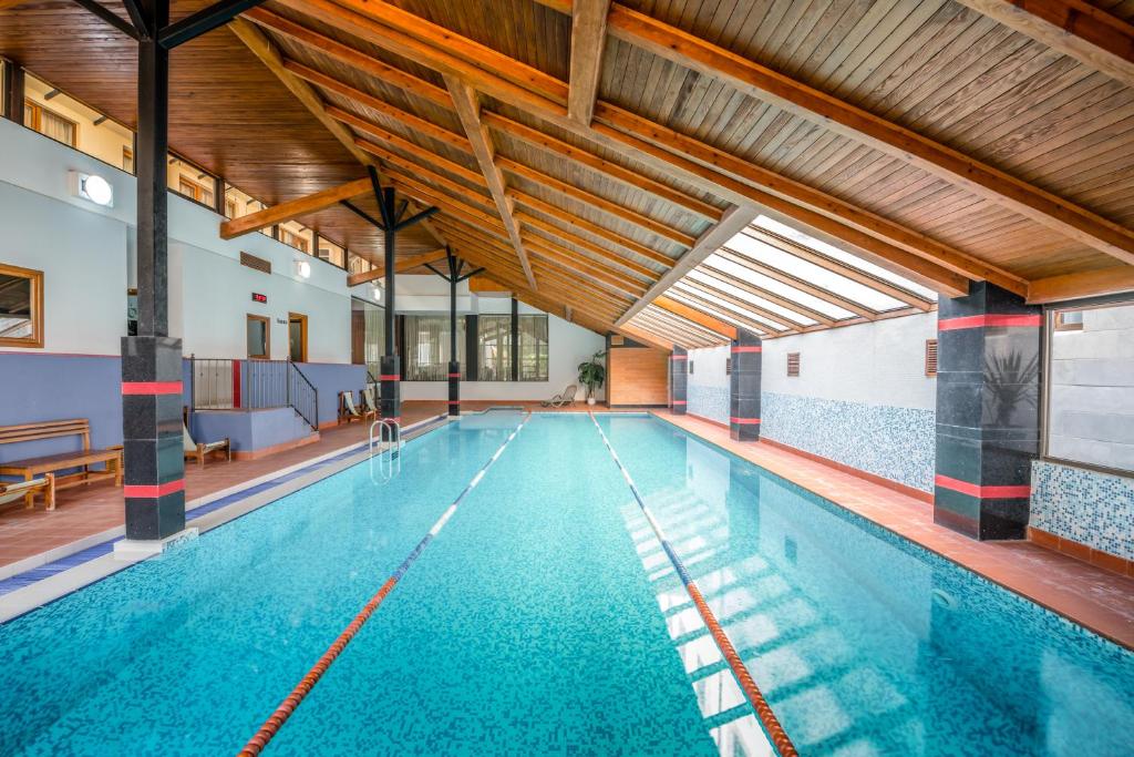 an indoor swimming pool with blue water at Kopala Tskneti Hotel in Tsqnetʼi