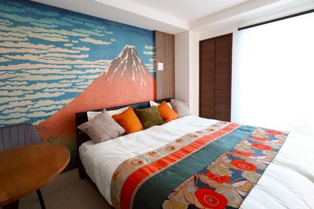 a bedroom with a bed with a painting on the wall at たびあかりn in Nishi-nakasange