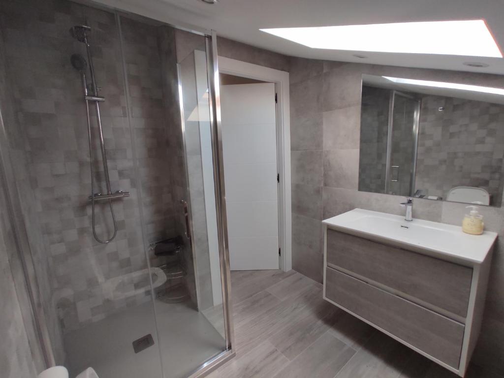a bathroom with a shower and a sink and a mirror at Villa Playa del Silencio in Castañeras