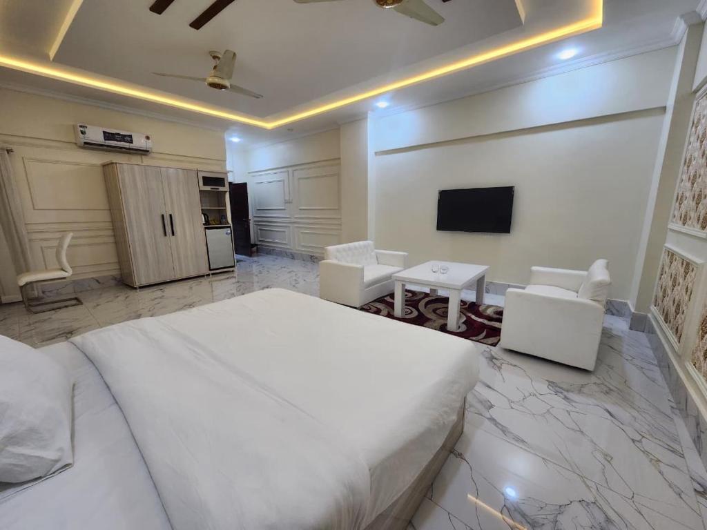 a bedroom with a large white bed and a tv at Pc Inn Executive Class Hotel in Sukkur