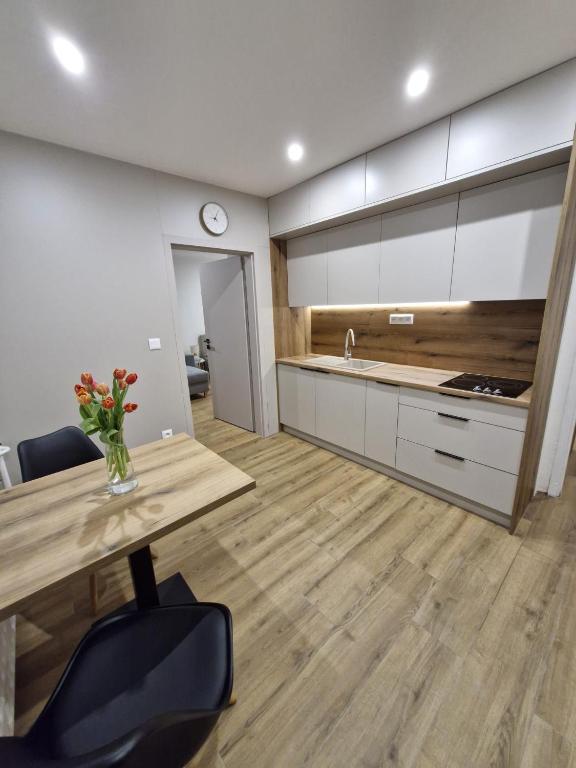 a kitchen with a wooden table and a vase of flowers at Apartmán Grand in Partizánske