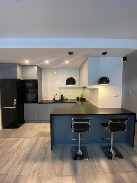 a kitchen with two bar stools in the middle at Apartament AquaTower, Aquapark Reda in Reda