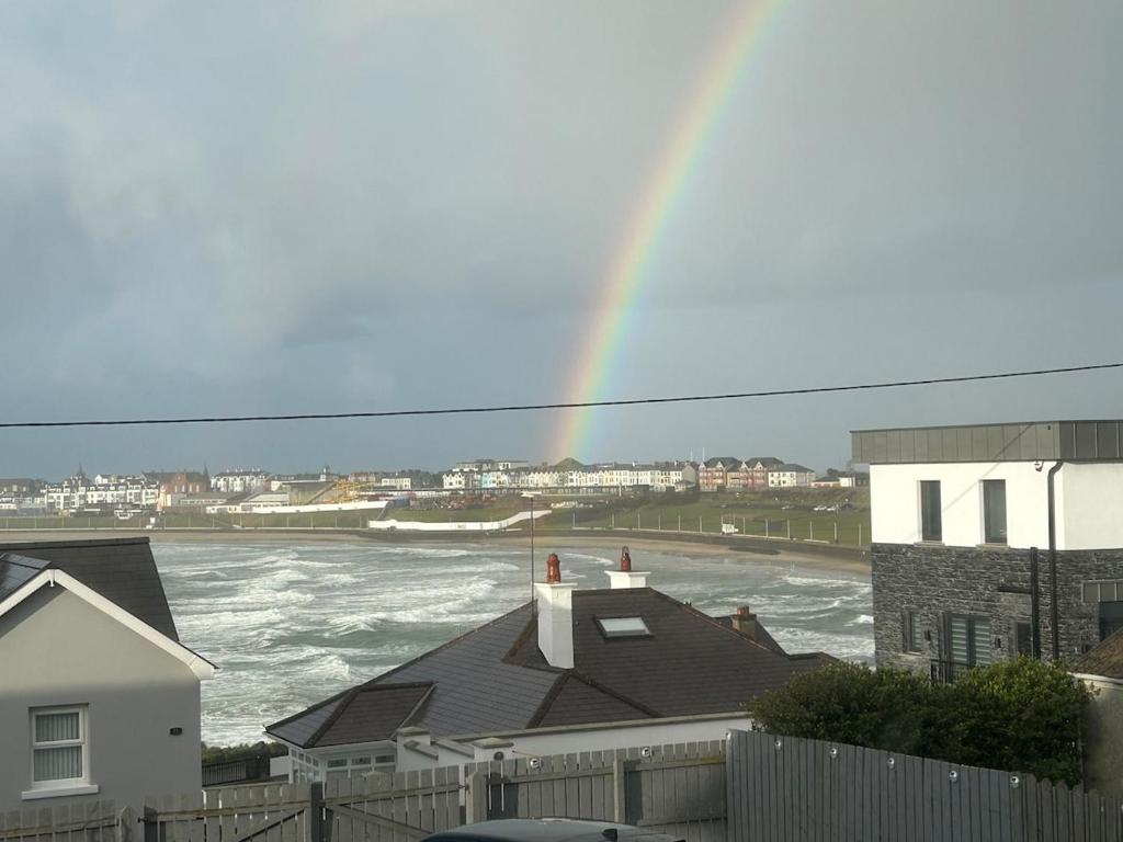 a rainbow over the water with a house at Blackhill Lookout in Portrush