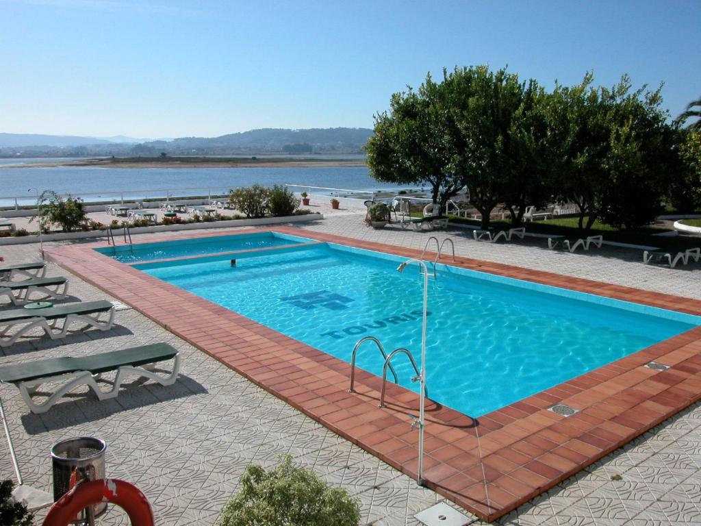 ein großer Pool neben einem Wasserkörper in der Unterkunft Hotel Touris in O Grove