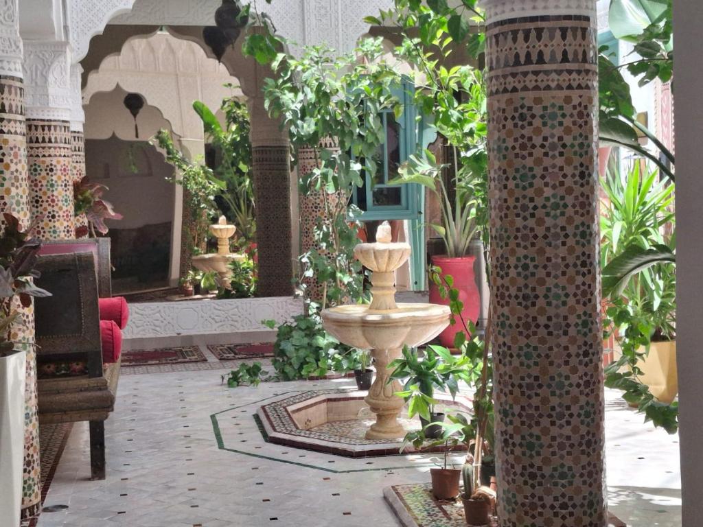a room with a fountain and plants in it at Riad Mille Et Une Nuits in Marrakesh