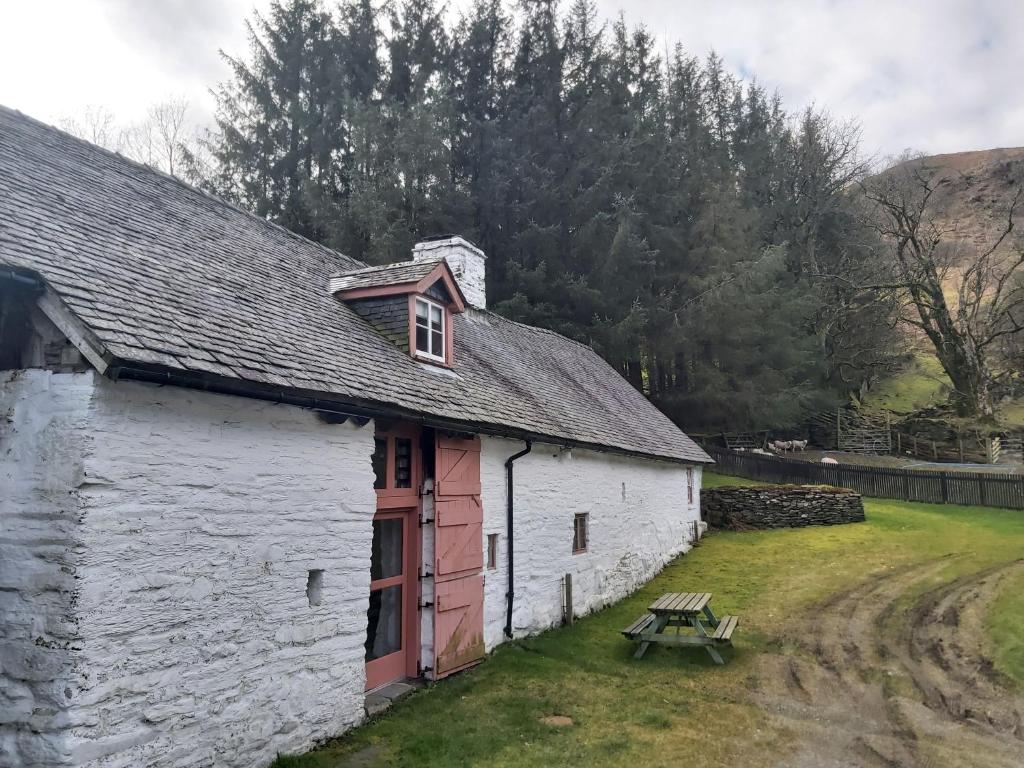 a white building with a picnic table in front of it at Longhouse - Y Beudy in Rhayader