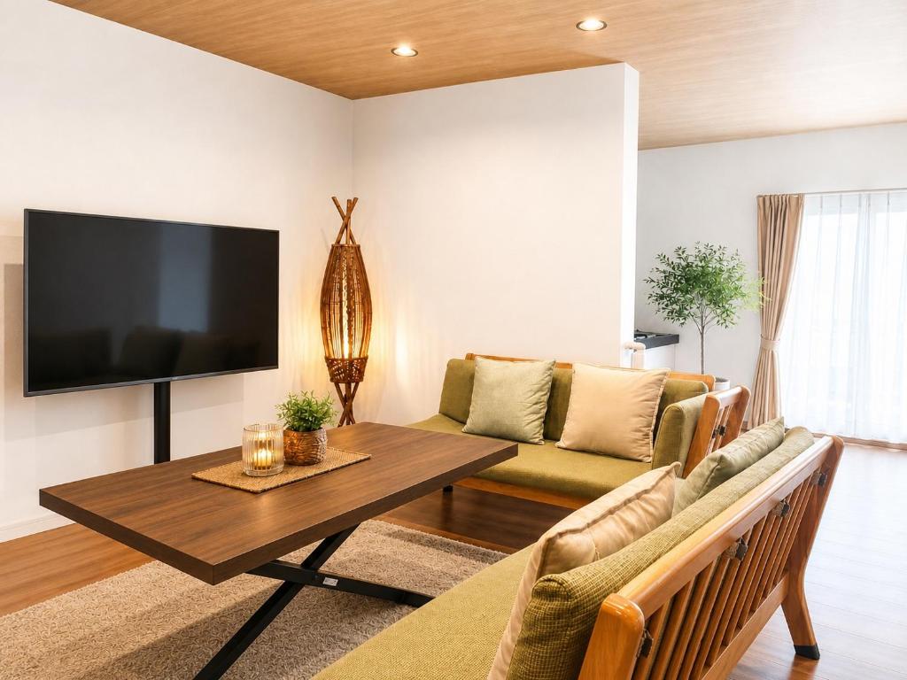 a living room with a tv and a couch and a table at TOMOSHIBI Kurashiki Zen House Near Bikan Historical Quarter 美観地区近く 和モダン一棟貸し in Kurashiki