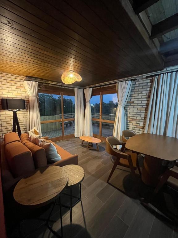 a living room with a couch and tables and windows at Luz de Arcturus, Chalé com jacuzzi aquecida in Imbituba