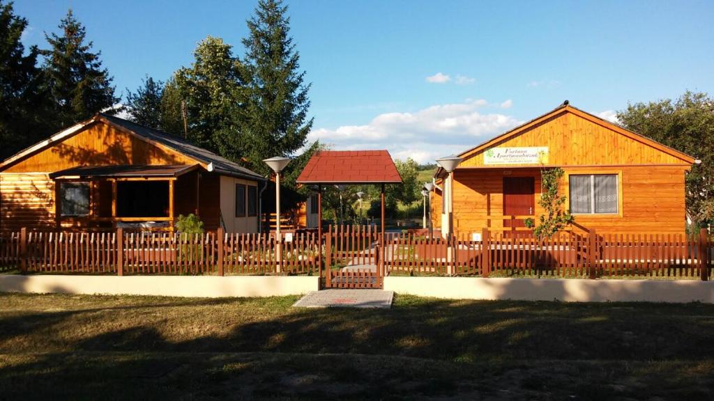a house with a wooden fence in front of it at Fortuna Apartmanházak in Bogács