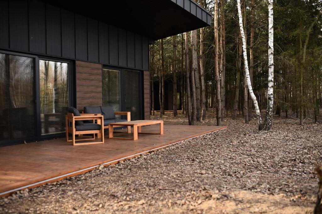 a house with a wooden deck with a table and a chair at Szept Lasu in Żabiczyn