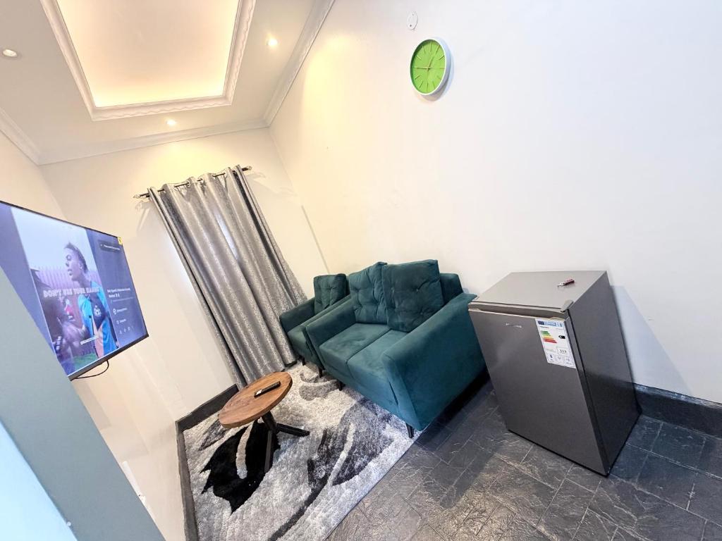a living room with a blue chair and a clock at Perfect Homes Namugongo in Kasiyirize