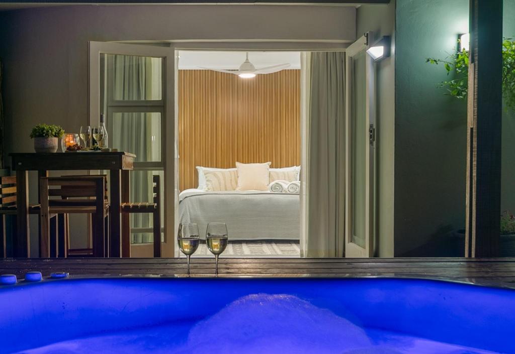 a bedroom with a bed and two glasses of wine at Lagoon Point Lodge in Knysna