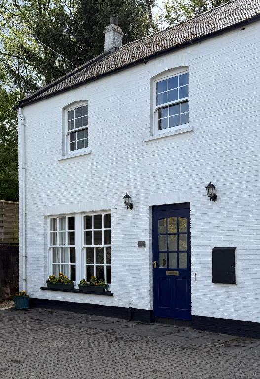 a white building with a blue door and windows at The Ship Inn's Cabin in Gatehouse of Fleet