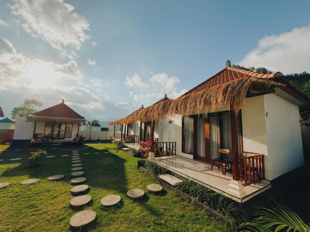 a house with a straw roof and a grass yard at Batur Tropical in Kintamani