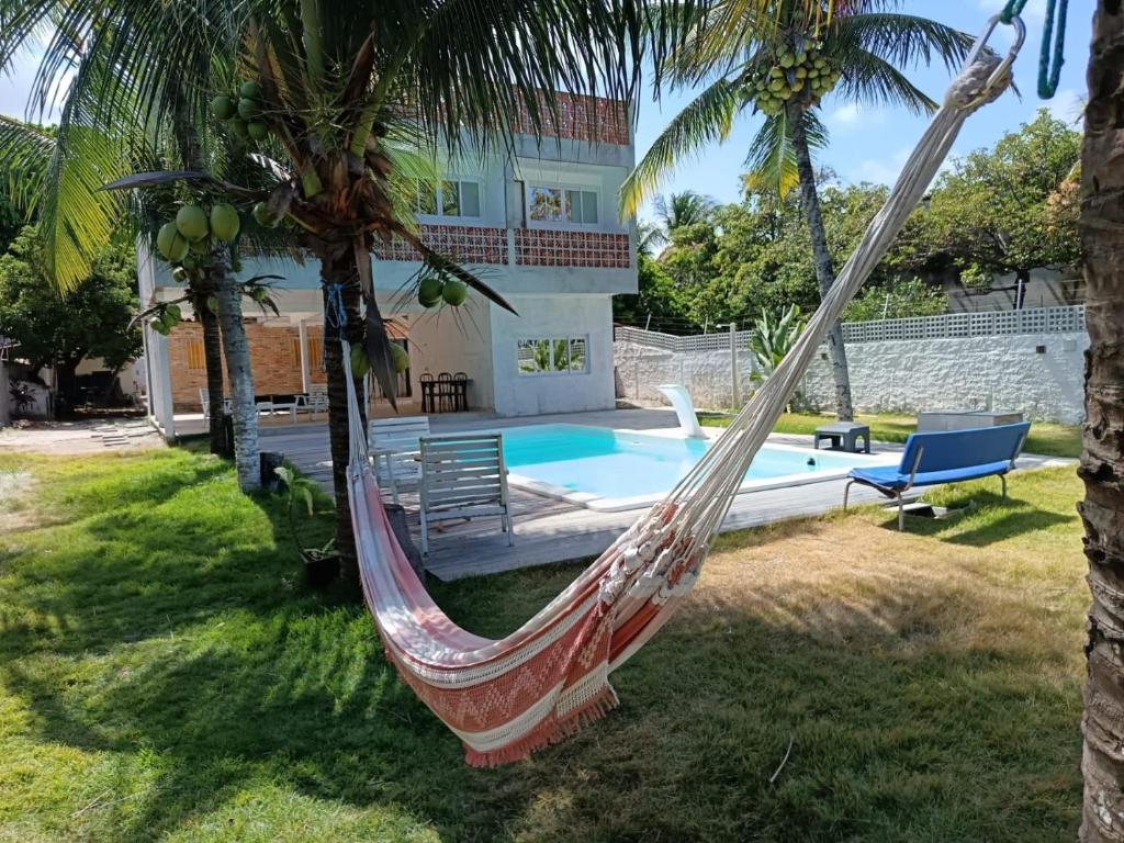 a hammock in front of a house with a pool at Kitnet Terreo Privada 1 in Conde